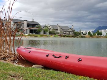 Boats in river by buildings against sky