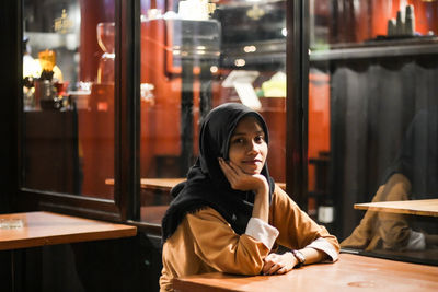 Portrait of smiling young woman sitting at table