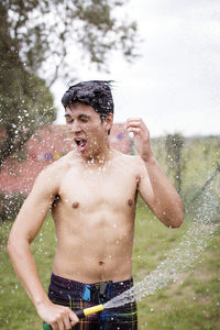 Excited man spraying water on self at yard