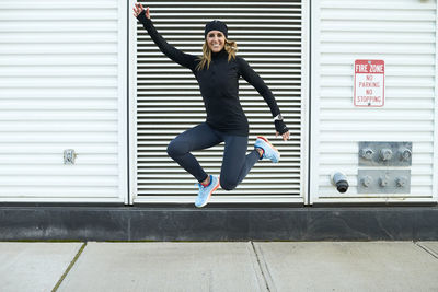 Full length of woman jumping against wall