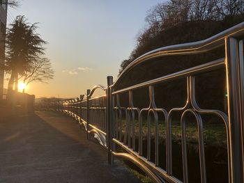 Empty footpath by railing against sky