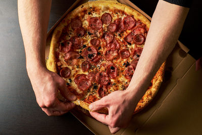 High angle view of hand holding pizza