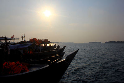 Boat moored in sea against sky during sunset