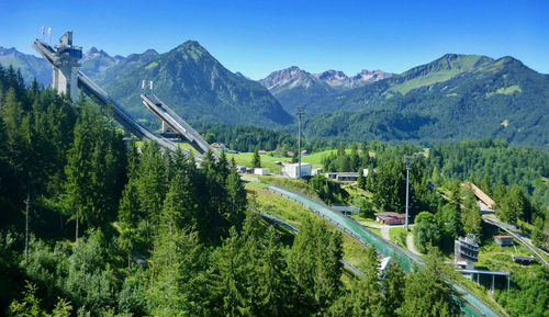 Panoramic shot of road amidst trees and mountains against sky