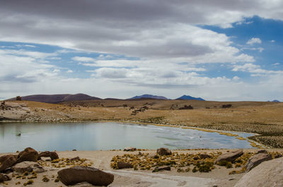 Scenic view of lake and landscape against cloudy sky at atacama desert