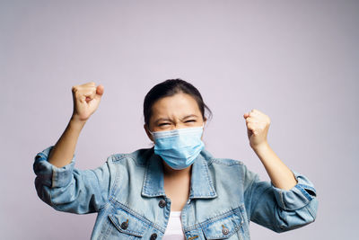 Young women wearing face mask against wall