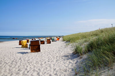 Hooded chairs on sand against sea at beach