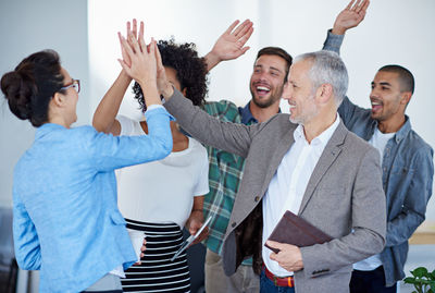 Business colleagues doing high five in office