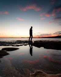 Silhouette man standing on beach against sky during sunset