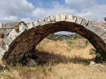 Arch bridge on field against sky