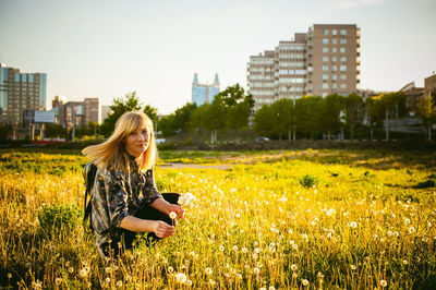 Portrait of woman relaxing amidst plants against buildings