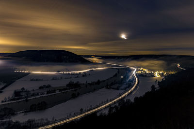 Aerial view of illuminated snowcapped mountains against sky at night