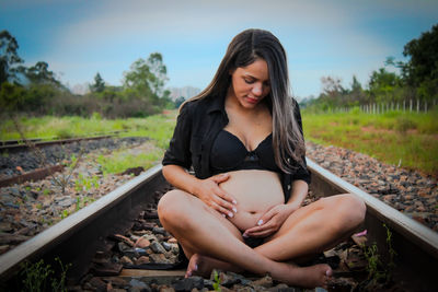 Young woman sitting on railroad track