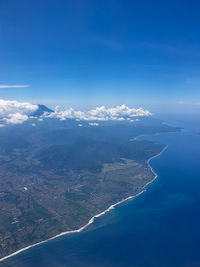 Aerial view of sea and mountains against blue sky