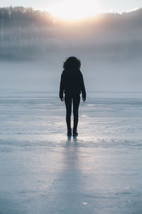 Full length of woman standing on snow covered field