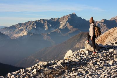 Rear view of person on rocks against mountains