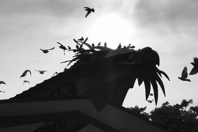 Low angle view of silhouette birds flying against sky