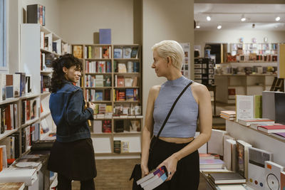 Lesbian couple glancing at each other while buying books from shop
