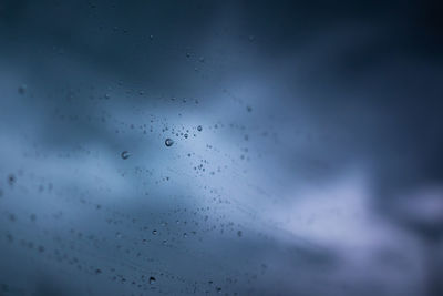 Low angle view of raindrops on glass window