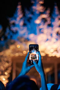 Low section of person photographing illuminated smart phone at night