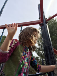 Low angle view of girl on play equipment at playground