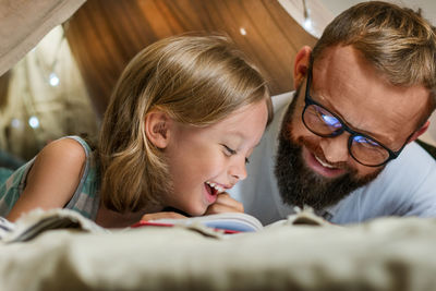 Father and son playing and reading in a kid tent at home.