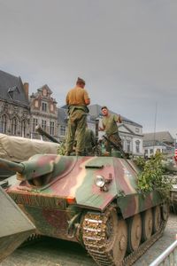 Rear view of people working in city against sky