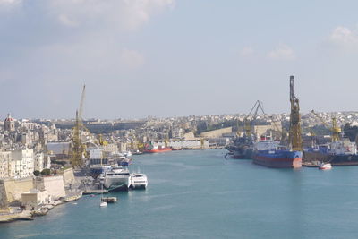 Boats moored in harbor by sea against sky