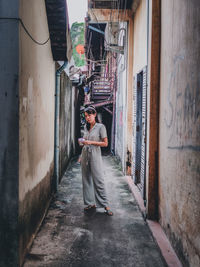 Woman standing on alley amidst buildings