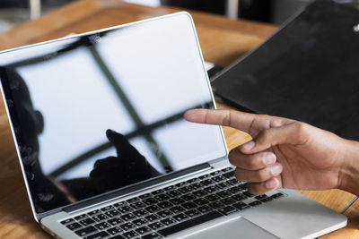 Cropped hands of woman using laptop at table