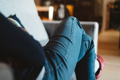 Low section of woman sitting on sofa at home