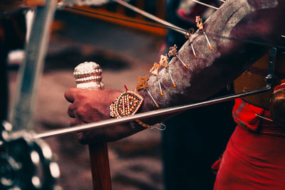 Close-up of a devotee's hand, adorned with vel and holding a walking stick, during thaipusam.