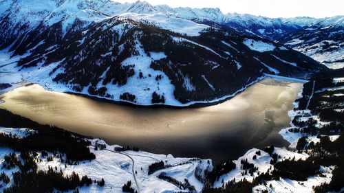 Aerial view of frozen lake by snowcapped mountain against sky