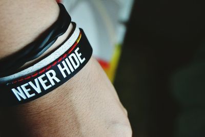 Cropped image of hand wearing bracelet with text