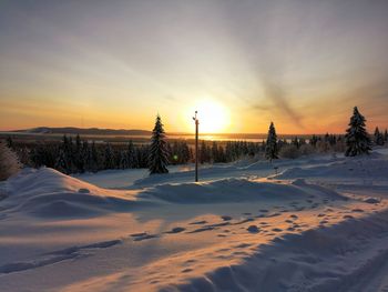 Scenic view of snow covered field against sky during sunset