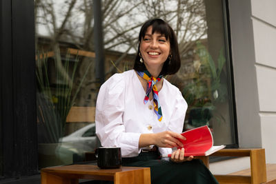 Smiling young woman holding book looking away