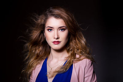 Portrait of beautiful young woman against black background