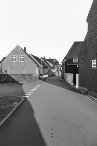 Empty road amidst buildings against sky