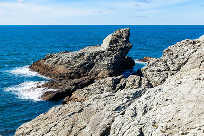 Rock formation on beach against sky