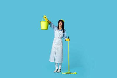 Rear view of woman holding shopping bags against blue background