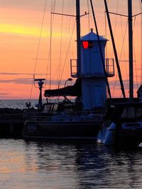 Boats sailing in sea at sunset