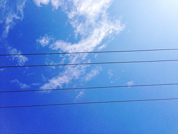 Low angle view of power lines against blue sky