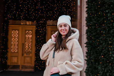 Portrait of smiling woman against christmas decoration during winter