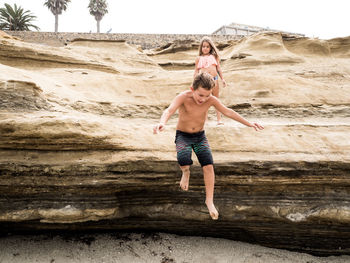 Full length of shirtless boy enjoying at beach