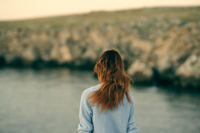 Rear view of woman standing against sky during sunset