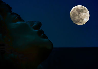 Cropped image of statue against full moon at night