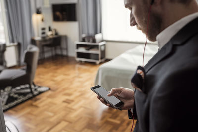 High angle view of businessman text messaging through mobile phone in hotel room