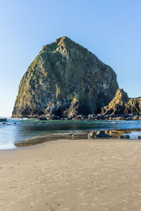 Rock formations on beach against clear sky