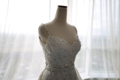 Close-up of wedding dress against curtain