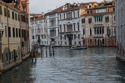 Boats in canal amidst buildings in city